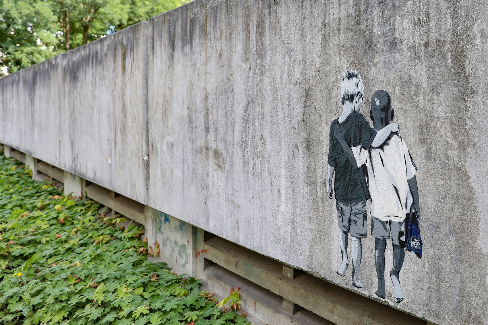 Mauer mit Graffiti von zwei Jungen, die den Arm umeinander gelegt haben.