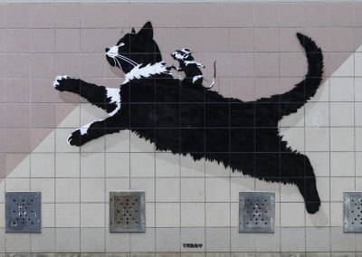 Street Art Wandgemälde vom Artist Tabby. Zusehen ist eine springende Katze, auf der eine kleine Maus reitet.